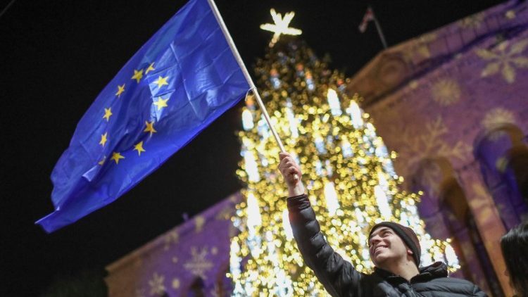 Um apoiador da oposição georgiana segura a bandeira georgiana durante um protesto em frente ao Parlamento georgiano em Tbilisi, Geórgia, 22 de dezembro de 2024. EPA/DAVID MDZINARISHVILI